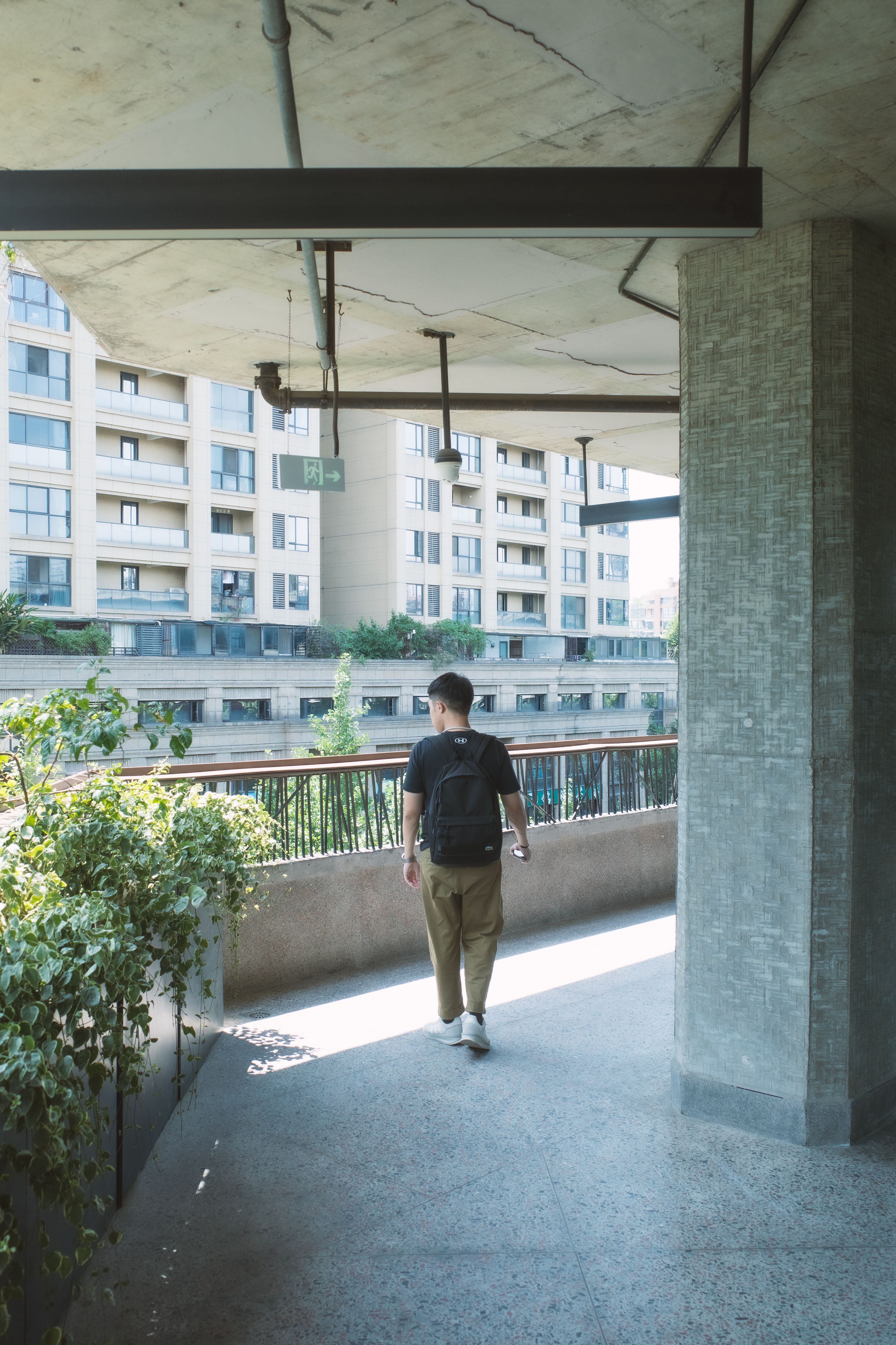 A man with a backpack walks through a modern urban setting in Chengdu, China.