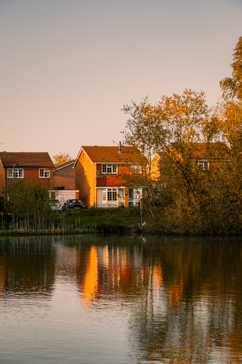 Free Picturesque scene of suburban homes by a pond at sunset in England. Stock Photo