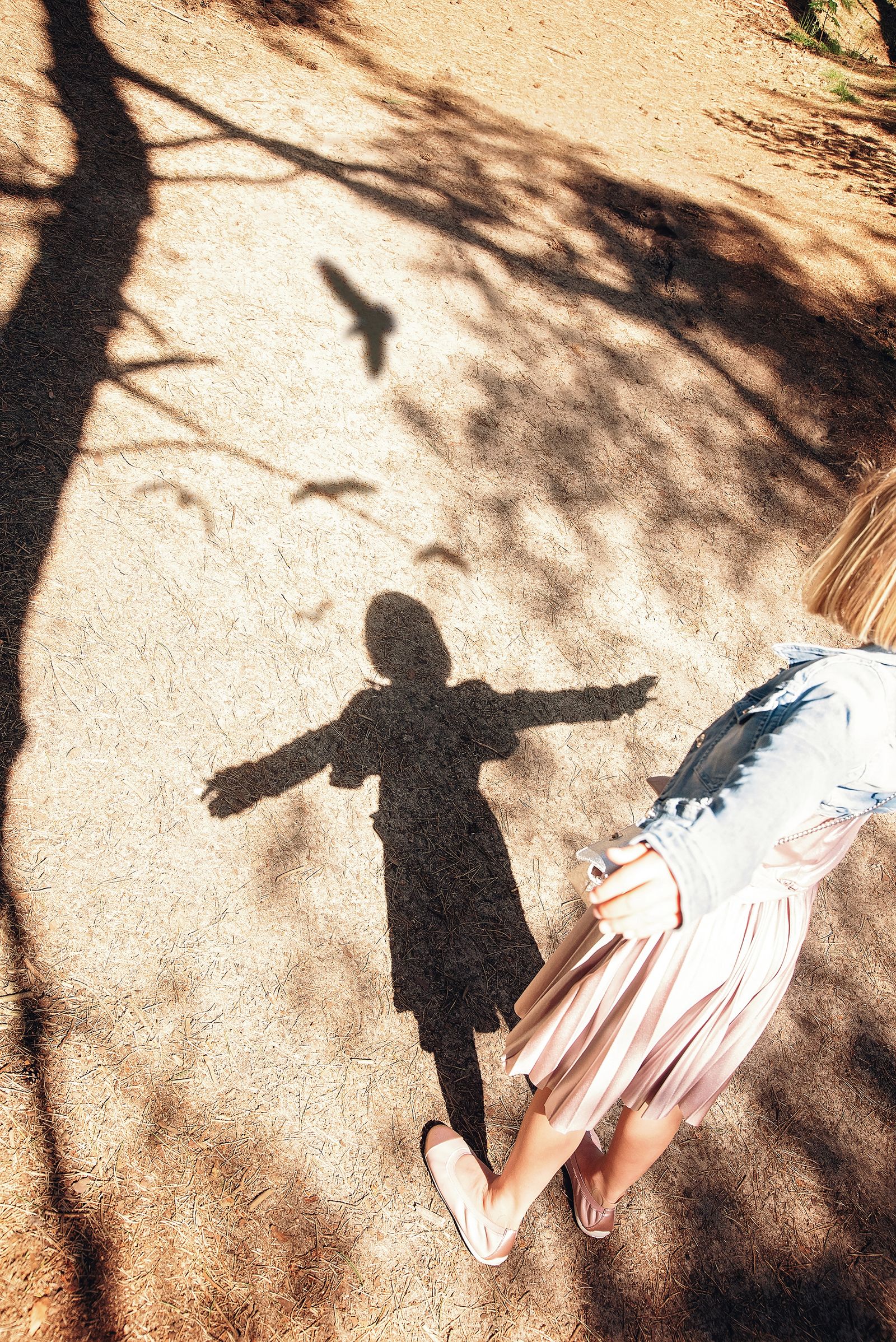 Une enfant joue avec son ombre sur le sol.