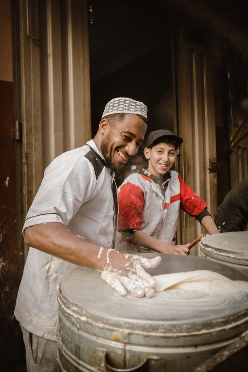 Free Cheerful bakers working with dough in a cozy, rustic kitchen setting. Stock Photo