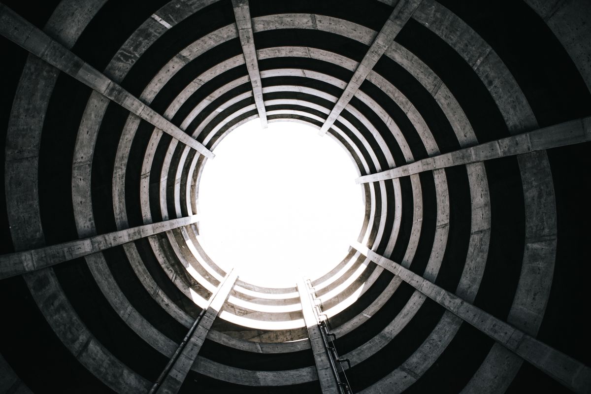 View from inside a circular concrete structure with a spiral staircase leading upward, illustrative photo