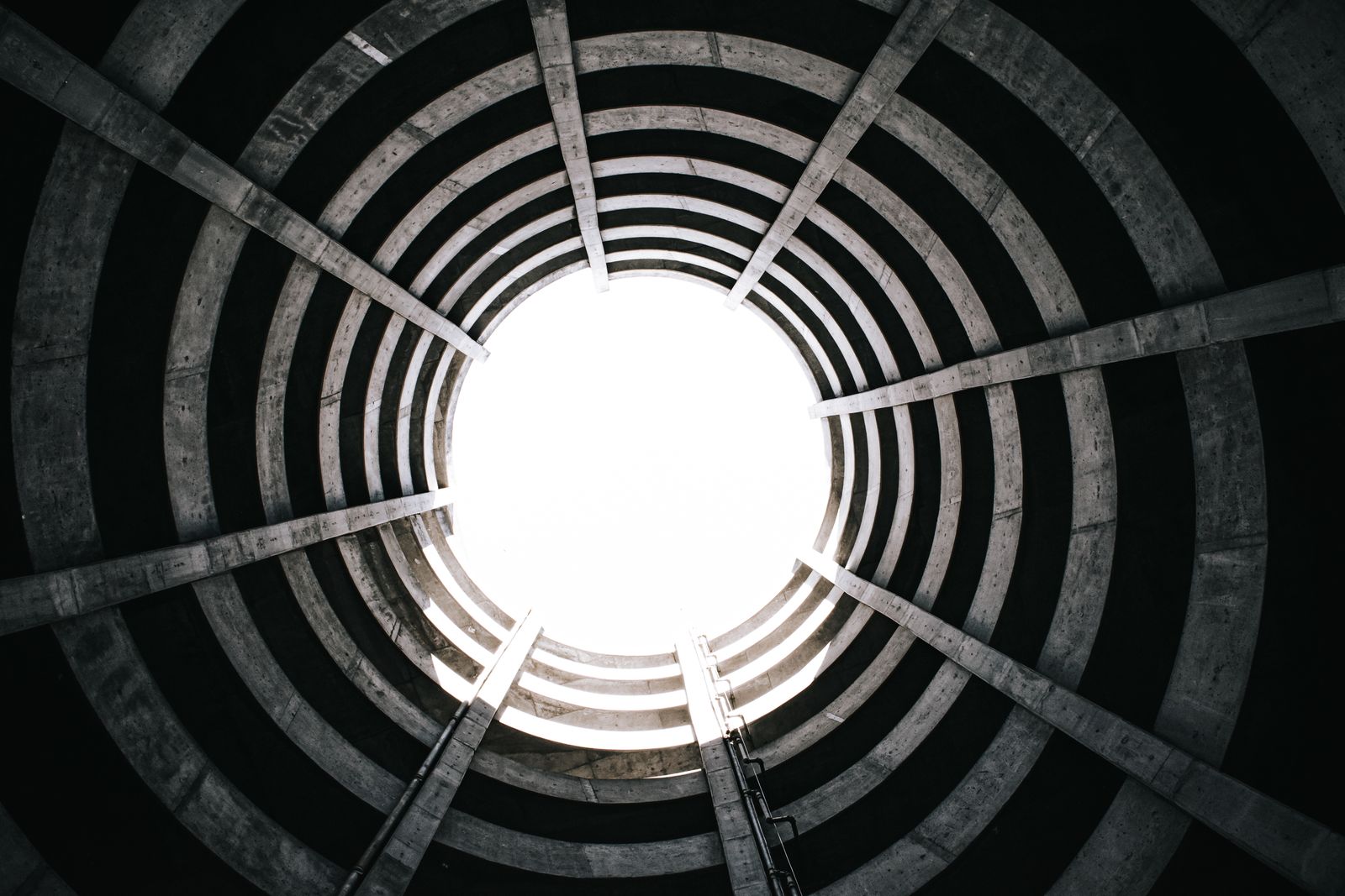 View from inside a circular concrete structure with a spiral staircase leading upward, illustrative photo