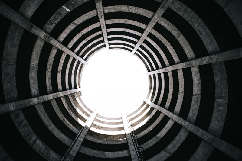 View from inside a circular concrete structure with a spiral staircase leading upward, illustrative photo