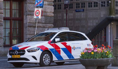 Free Dutch police vehicle parked near street signs with colorful tulips in foreground. Stock Photo