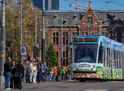 Vibrant city life with a Ben & Jerry's tram and diverse crowd in Amsterdam.