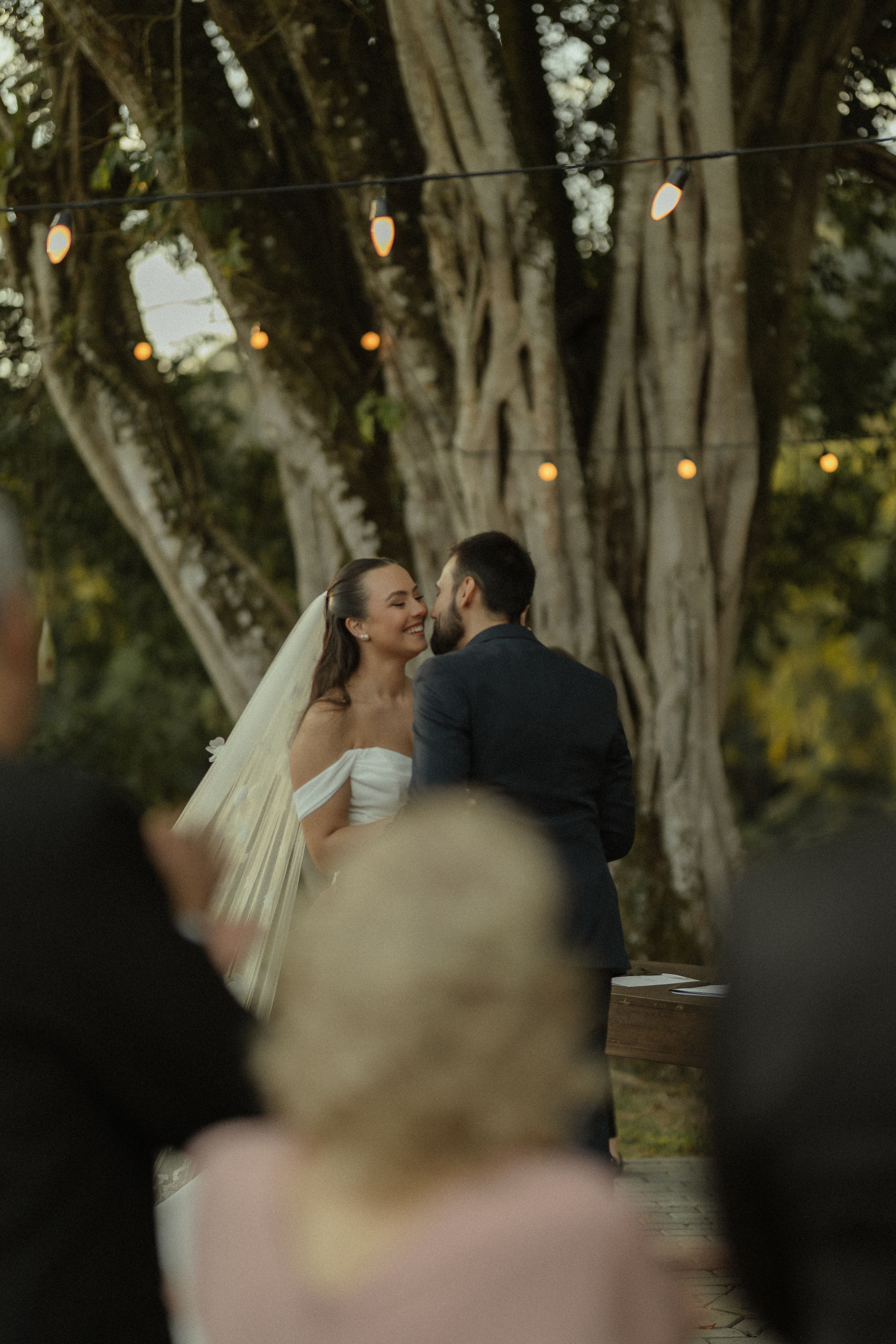 A beautiful outdoor wedding ceremony with a bride and groom sharing a joyful moment under string lights.