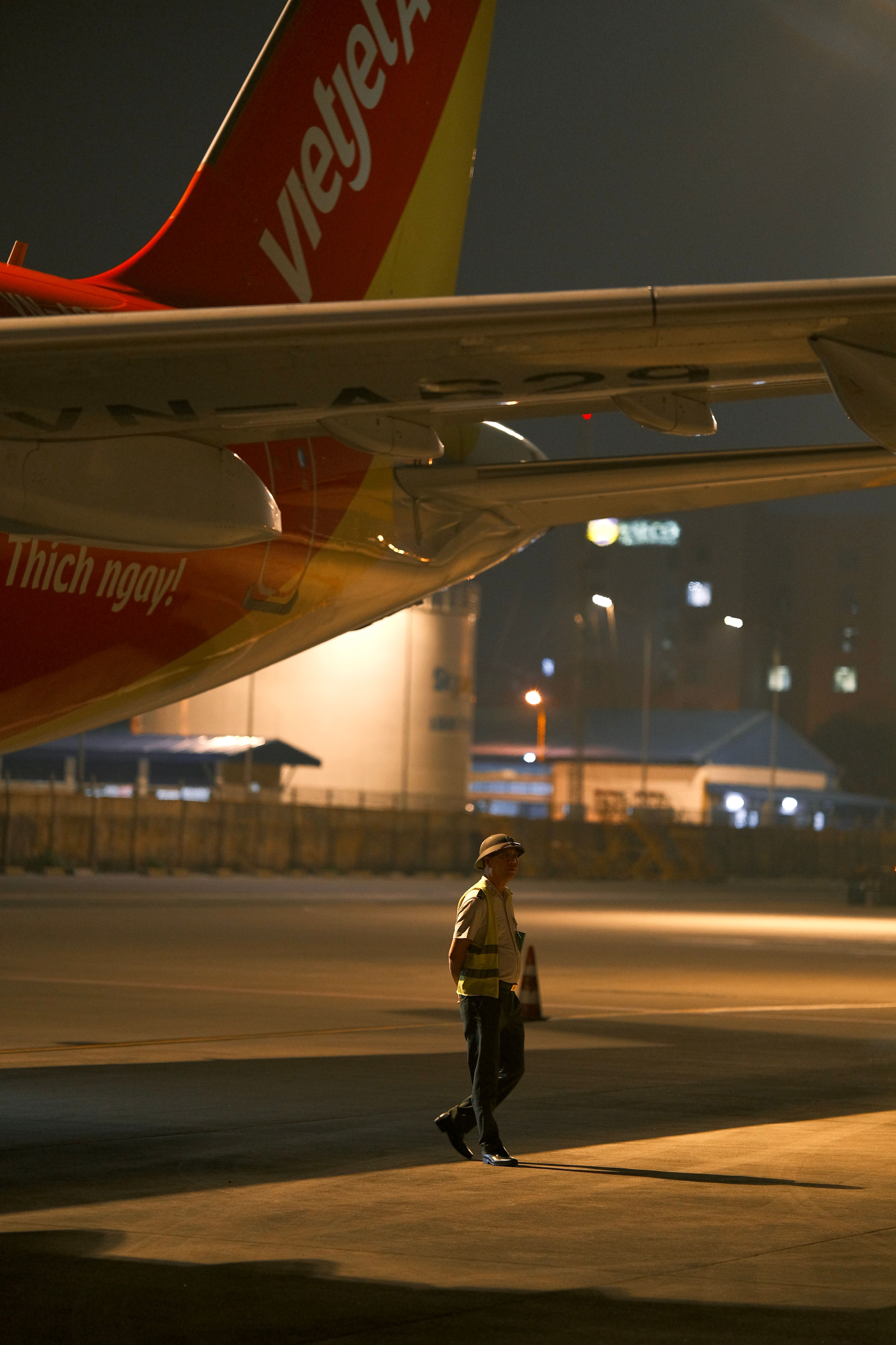 A technician inspects an aircraft at night on a Vietnamese airport tarmac.