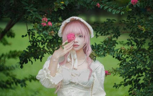 Free Portrait of a woman in vintage clothing surrounded by vibrant flowers in a lush garden. Stock Photo