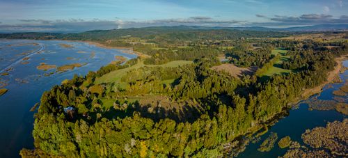 Free Breathtaking aerial panorama of a river surrounded by lush green forests and hills. Stock Photo