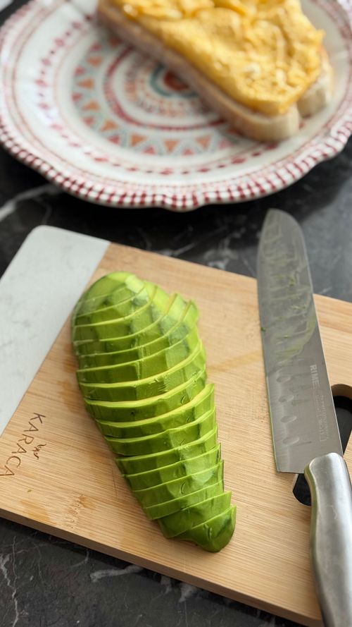 Free Freshly sliced avocado on a wooden board with bread in the background. Stock Photo