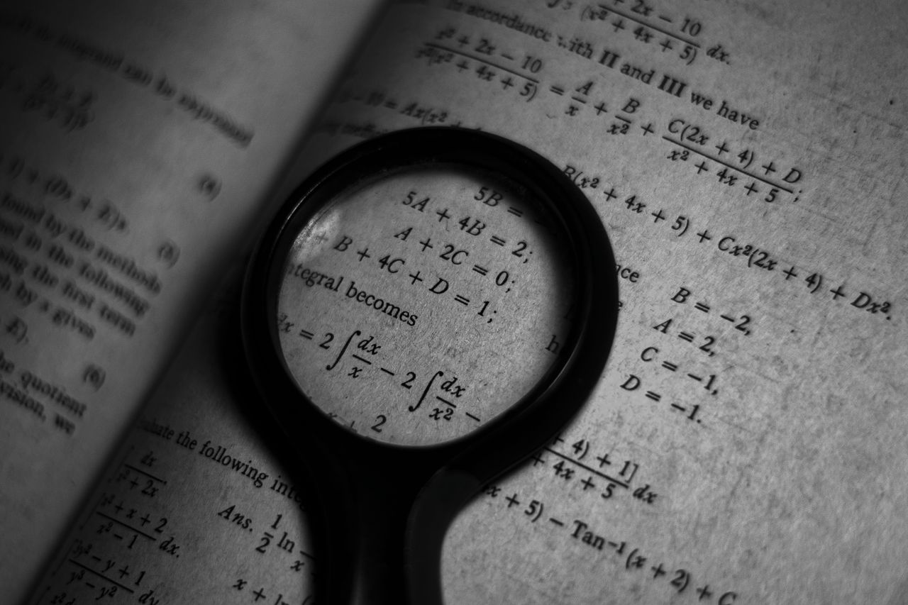 Una lupa enfoca fórmulas matemáticas en un libro de estudio.