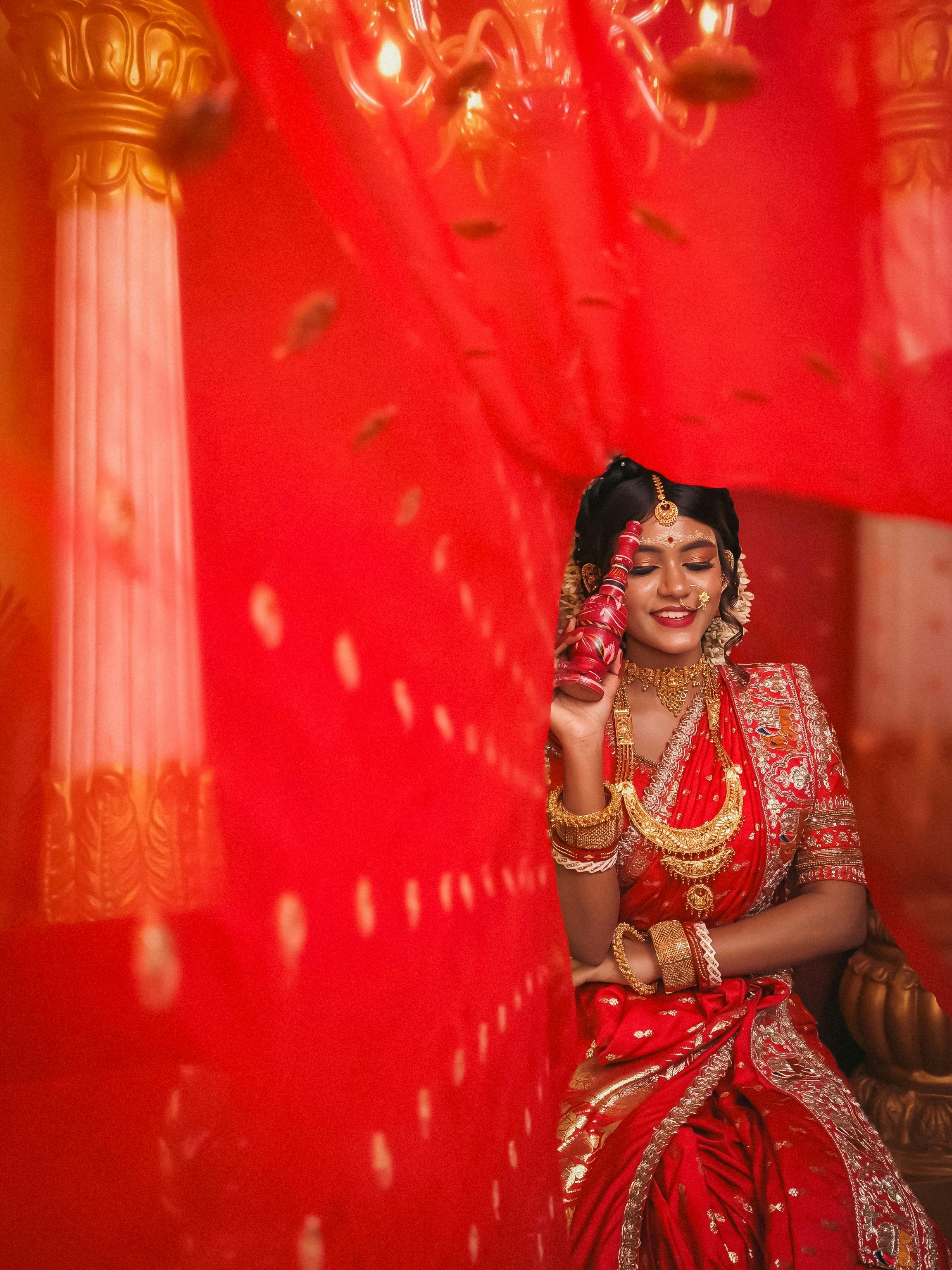 Elegant Bengali bride wearing traditional attire, adorned with bridal jewelry, captured in a vibrant setting.