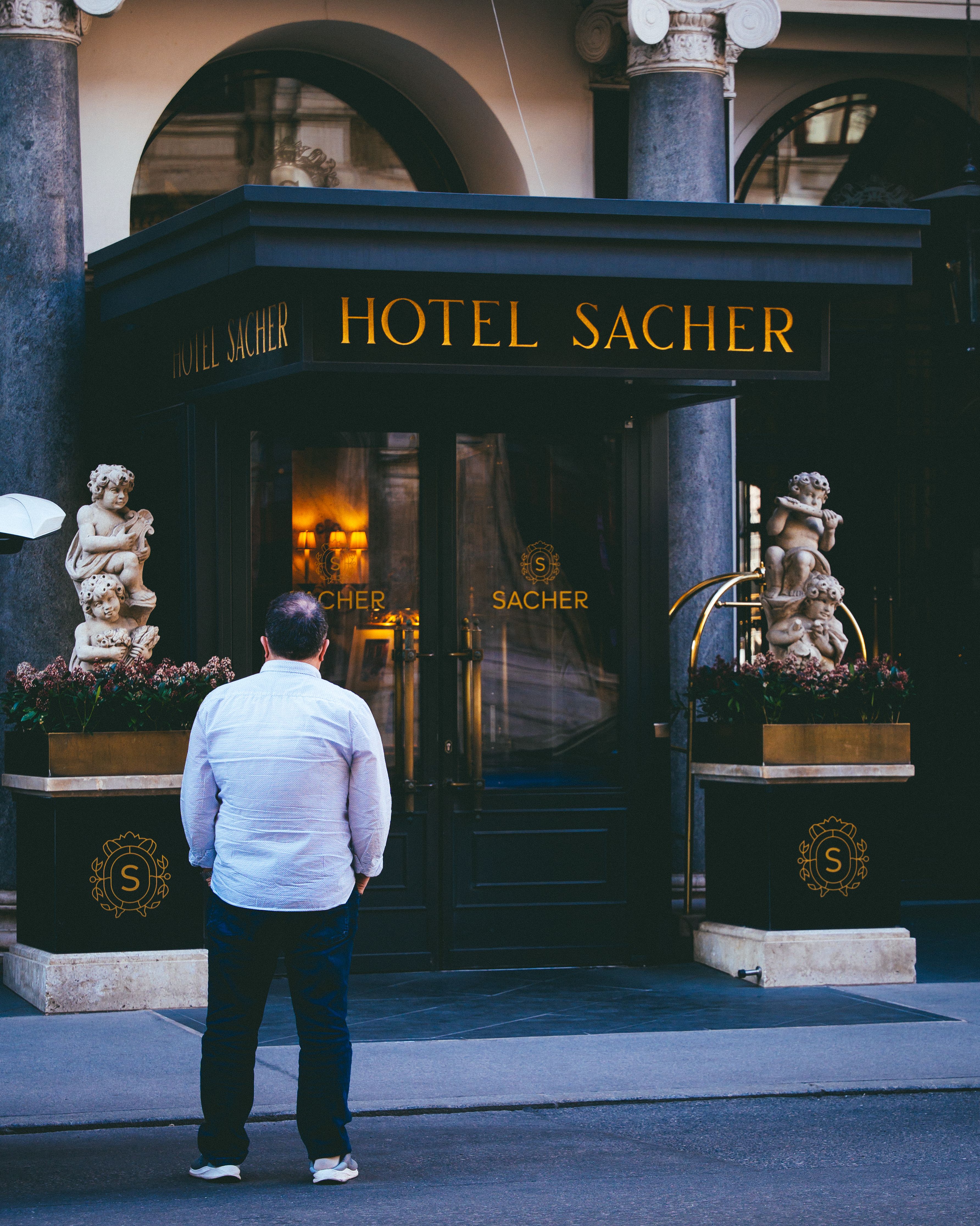 Person standing outside the iconic Hotel Sacher in Vienna, Austria, capturing its grandeur.