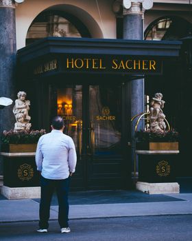 Person standing outside the iconic Hotel Sacher in Vienna, Austria, capturing its grandeur.