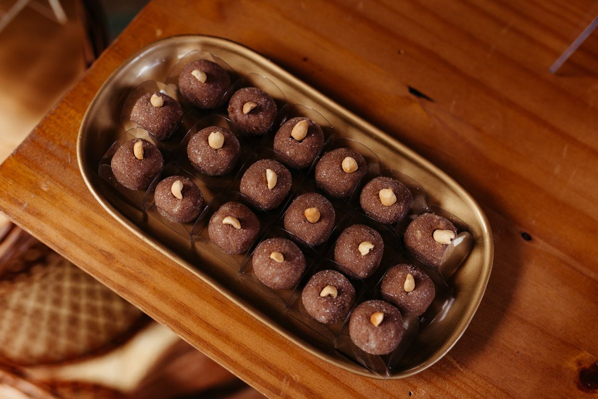 Top view of a tray of gourmet chocolate truffles with nuts on a wooden table, perfect for celebrations.