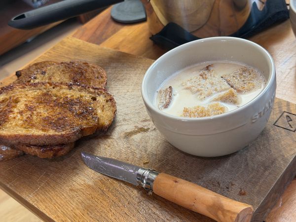 Tranches de pain grillé et bol de soupe aux croûtons sur une planche à découper