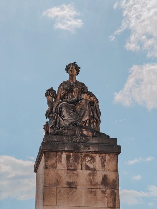 Free Artistic ancient stone statue against a bright blue sky, showcasing intricate details and rich history. Stock Photo