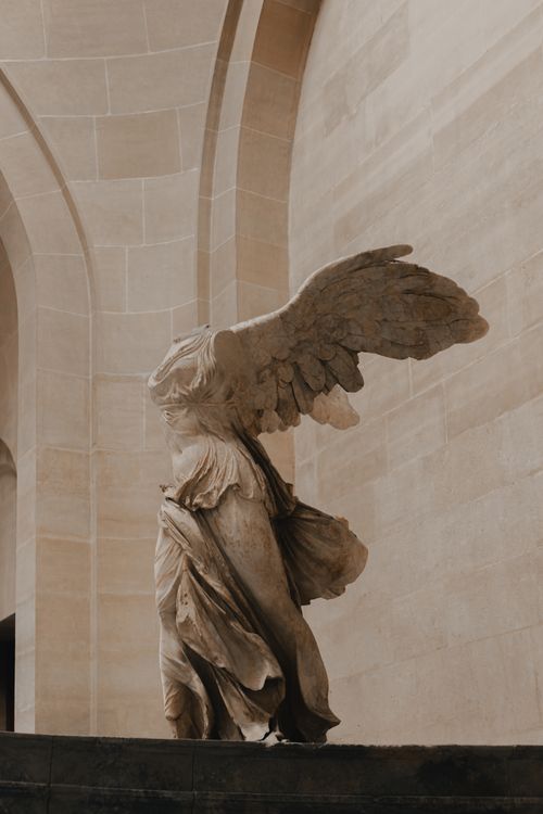 Free Elegant statue of Winged Victory of Samothrace on display in a classical museum setting. Stock Photo