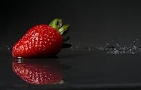 特写镜头中，光滑表面的新鲜草莓反射着光线
