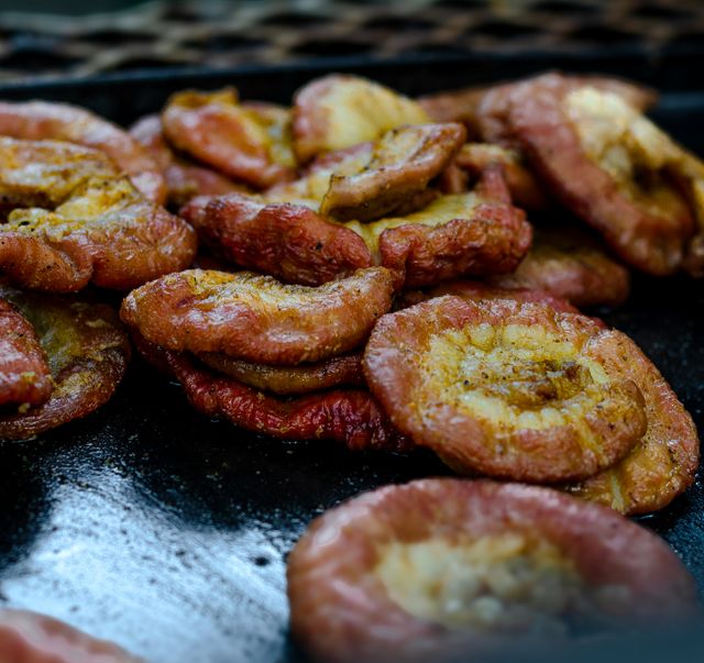 Deliciously golden fried plantains on a black griddle, showcasing traditional Latin American cuisine.