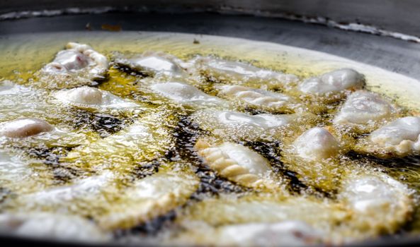 Delicious Argentine empanadas frying in hot oil, showcasing a traditional culinary process.