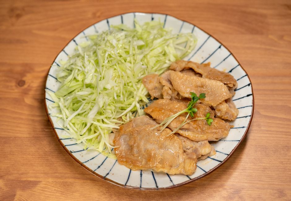 A pile of tender, shredded kalua pork glistening with rendered fat, served over sauteed cabbage on a white plate.