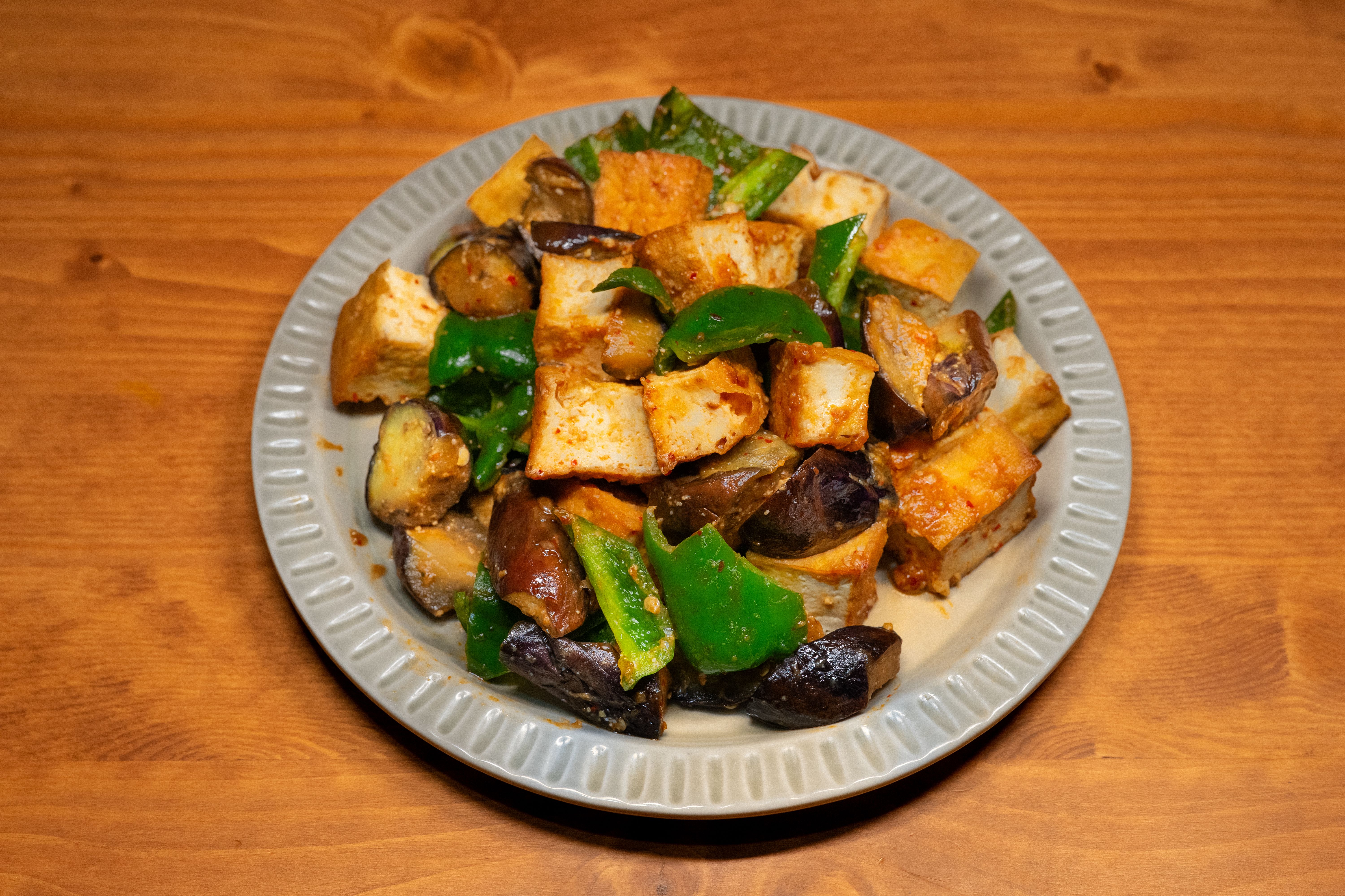 A vibrant dish of stir-fried tofu, eggplant, and bell peppers, showcasing colorful Asian cuisine.
