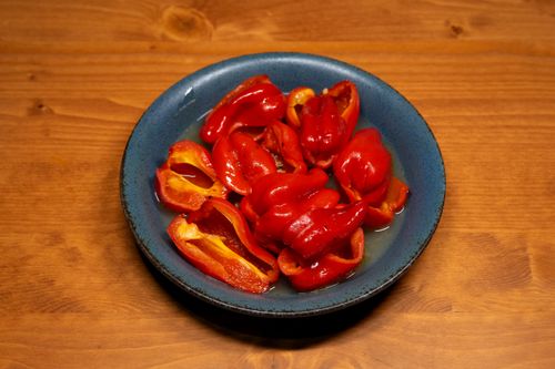 Free Fresh red bell peppers sliced and served on a rustic blue plate on a wooden table. Stock Photo