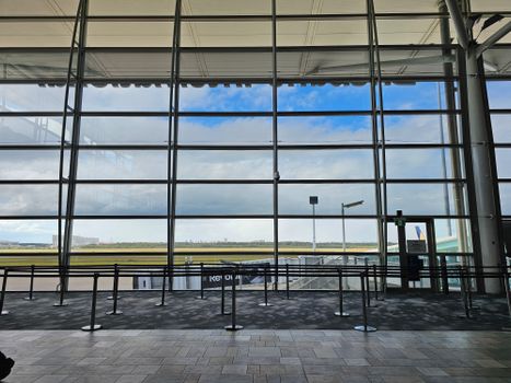 Large airport terminal with floor-to-ceiling windows offering a panoramic view of the sky and runway.