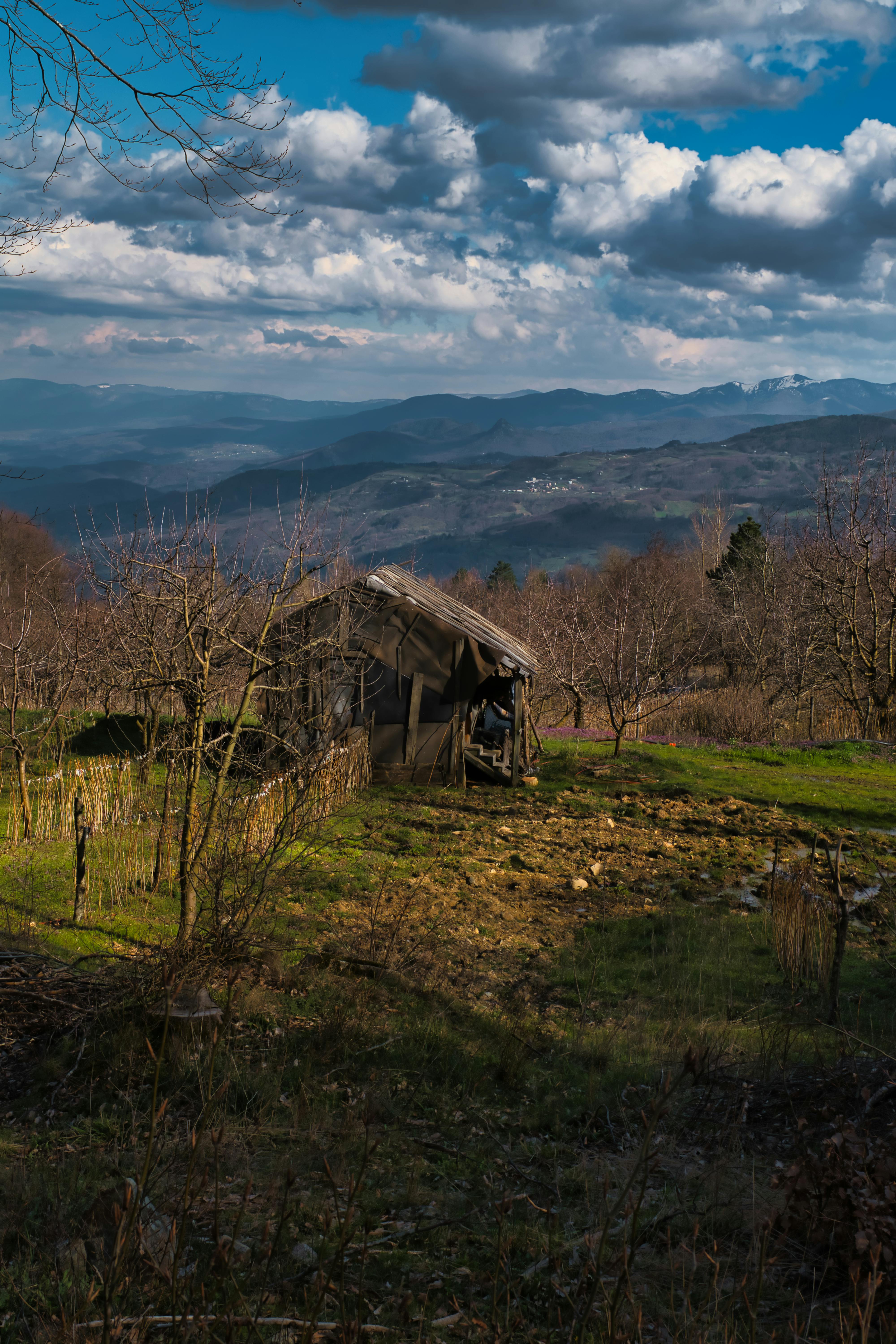 A wooden cabin amidst a serene mountainous landscape under a bright sky.
