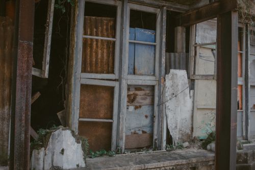 Free A rustic old building with shattered windows and peeling paint, conveying an abandoned feel. Stock Photo
