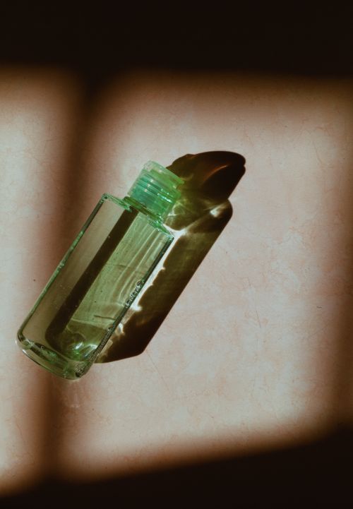 Free A glass bottle casting a dramatic shadow on a surface lit by sunlight, creating an artistic composition. Stock Photo