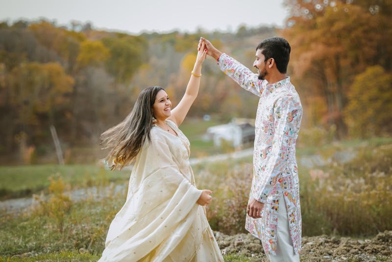 Joyful couple in traditional attire dancing among autumn foliage