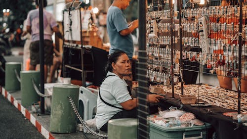 Wanita Berkemeja Putih Duduk Di Belakang Kios