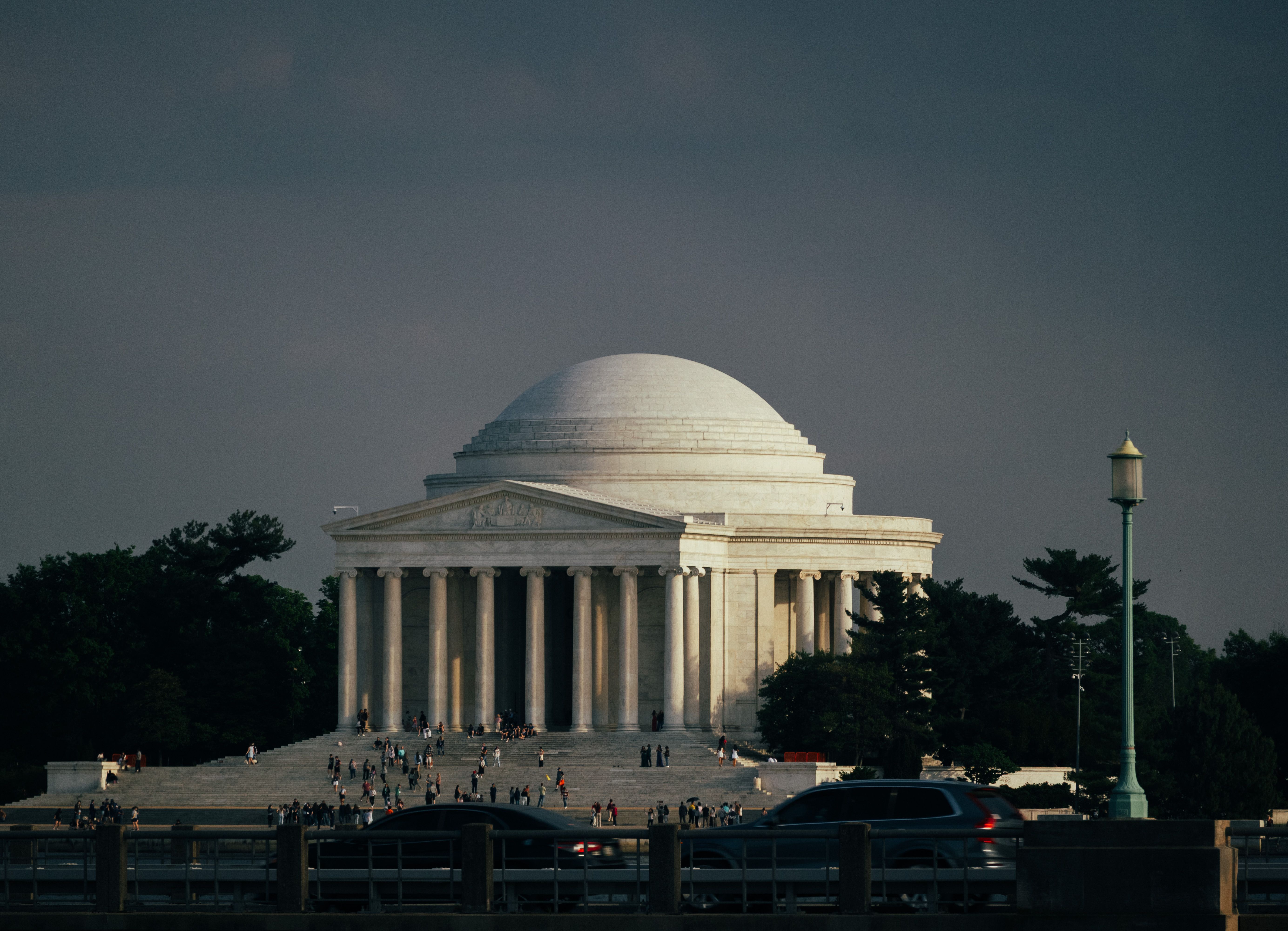 Stunning view of the Jefferson Memorial in Washington DC at sunset with people gathered outside.