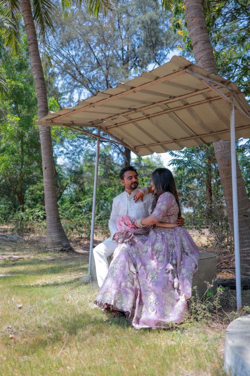 Free A happy couple poses under a rustic shelter in an outdoor setting during their wedding photoshoot. Stock Photo