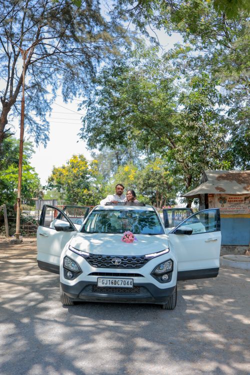 Free Happy married couple posing with a car on a sunny day, celebrating their wedding outdoors. Stock Photo