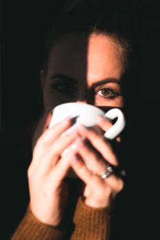 一个女人手持杯子，沉浸在晨光中，营造出宁静舒适的氛围
