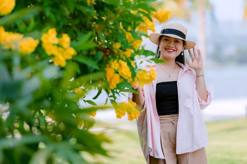 Free Smiling woman in a sunhat near vibrant yellow flowers outdoors. Stock Photo
