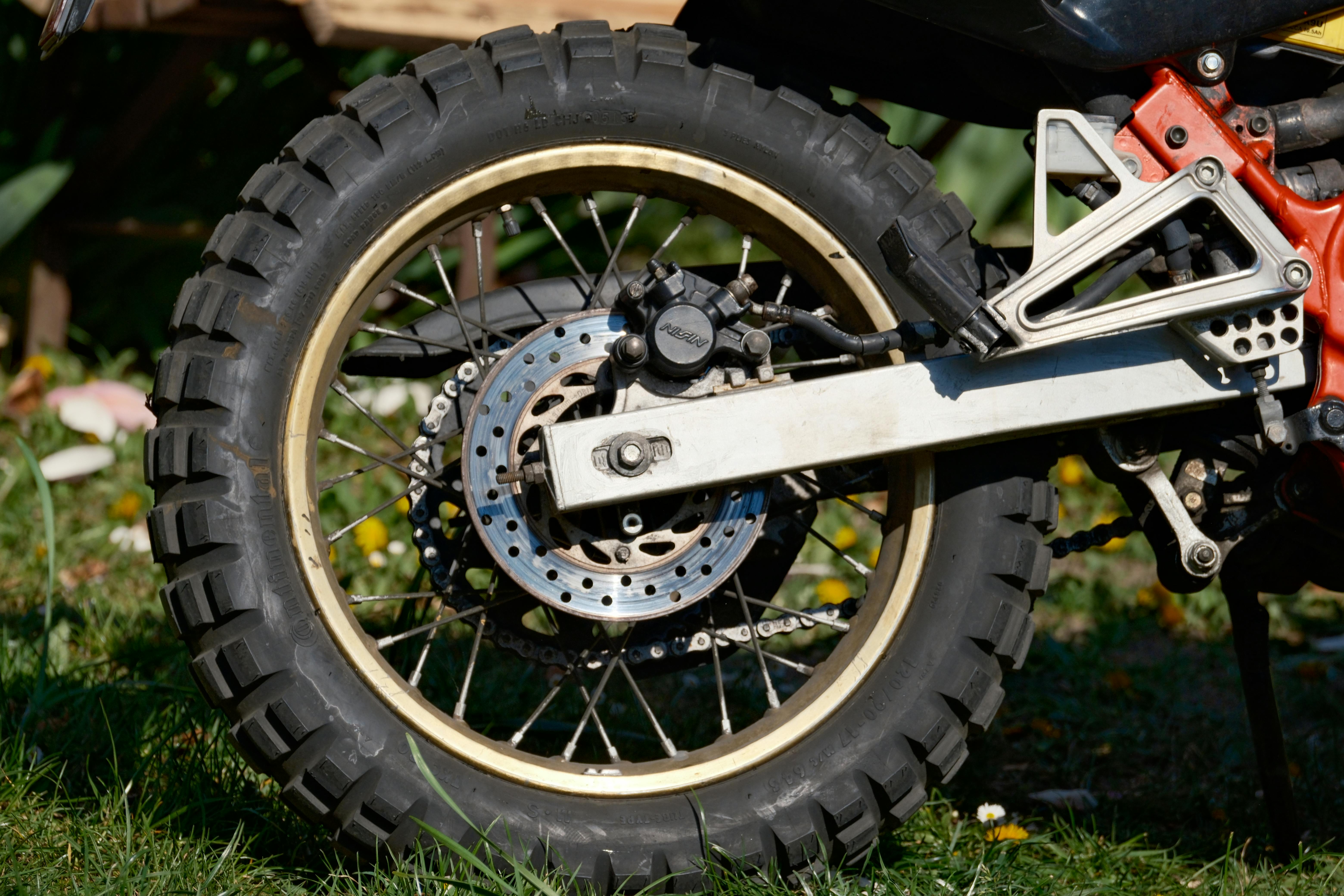 Detailed view of an off-road motorcycle wheel on grassy terrain.
