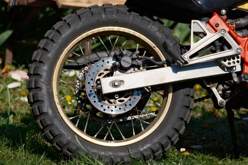 Free Detailed view of an off-road motorcycle wheel on grassy terrain. Stock Photo