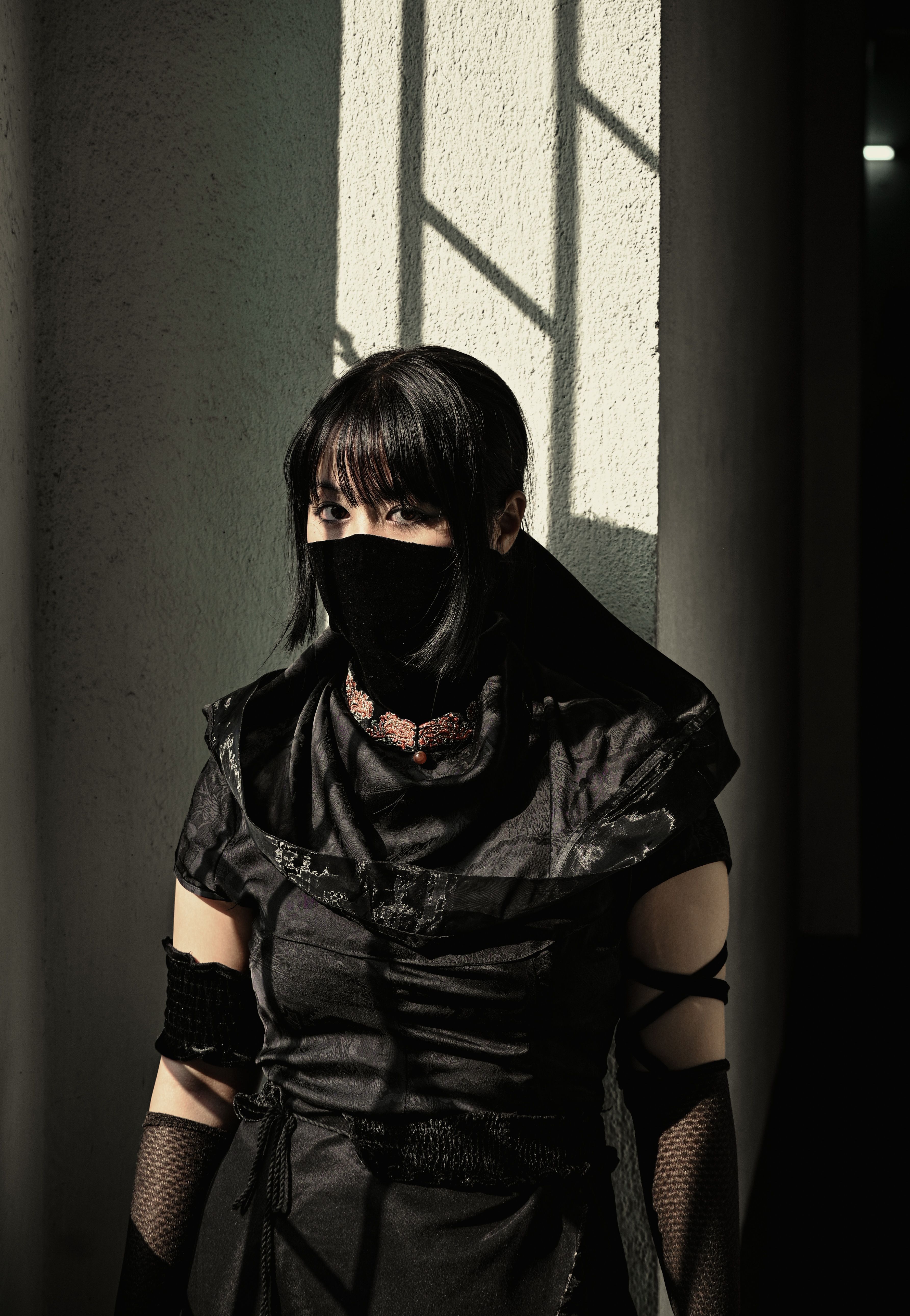 A woman in gothic attire stands in shadowy lighting, adding a mysterious aura.