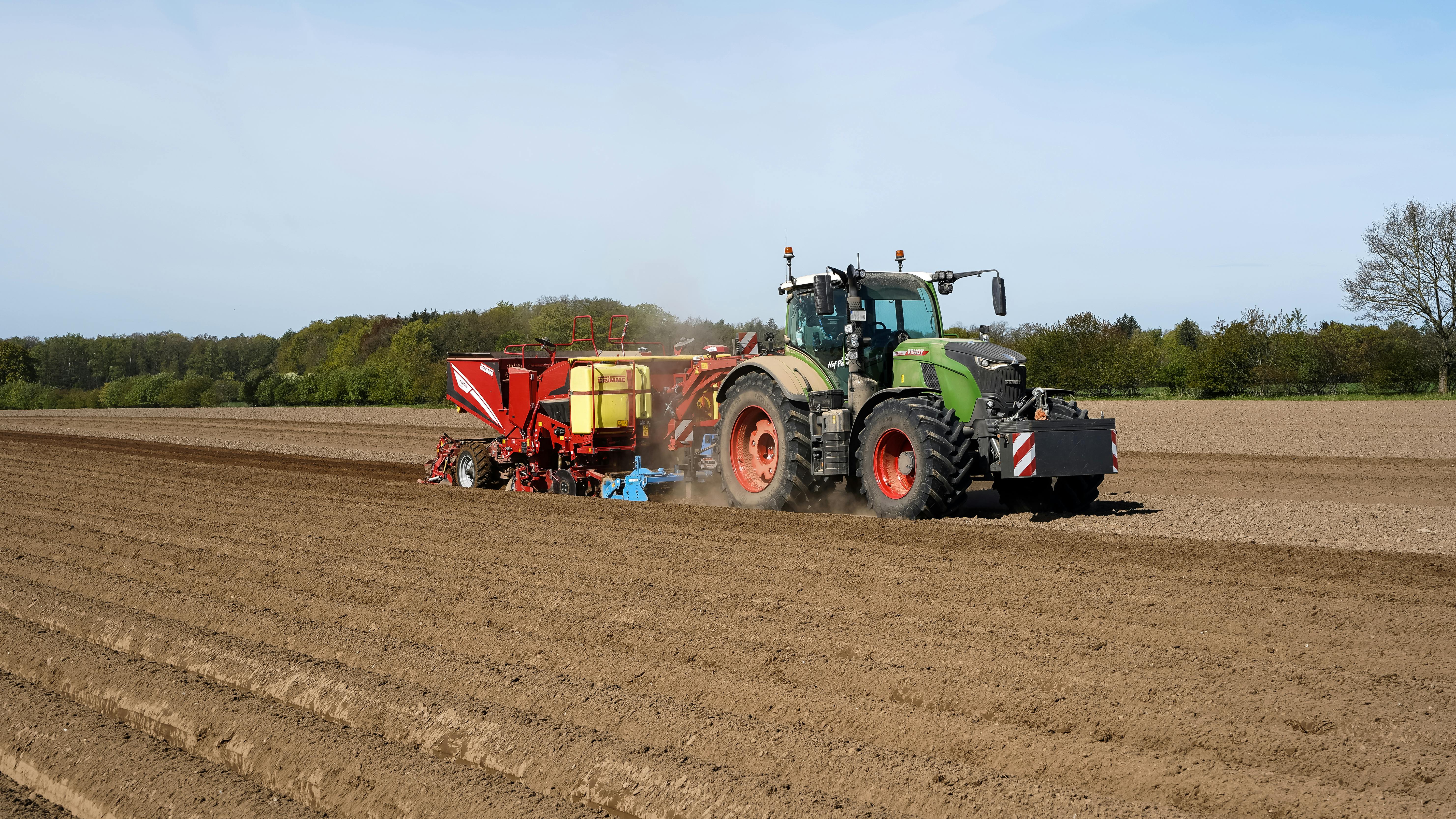 Tractor planting potatoes in Lütau, Germany during spring farming season.