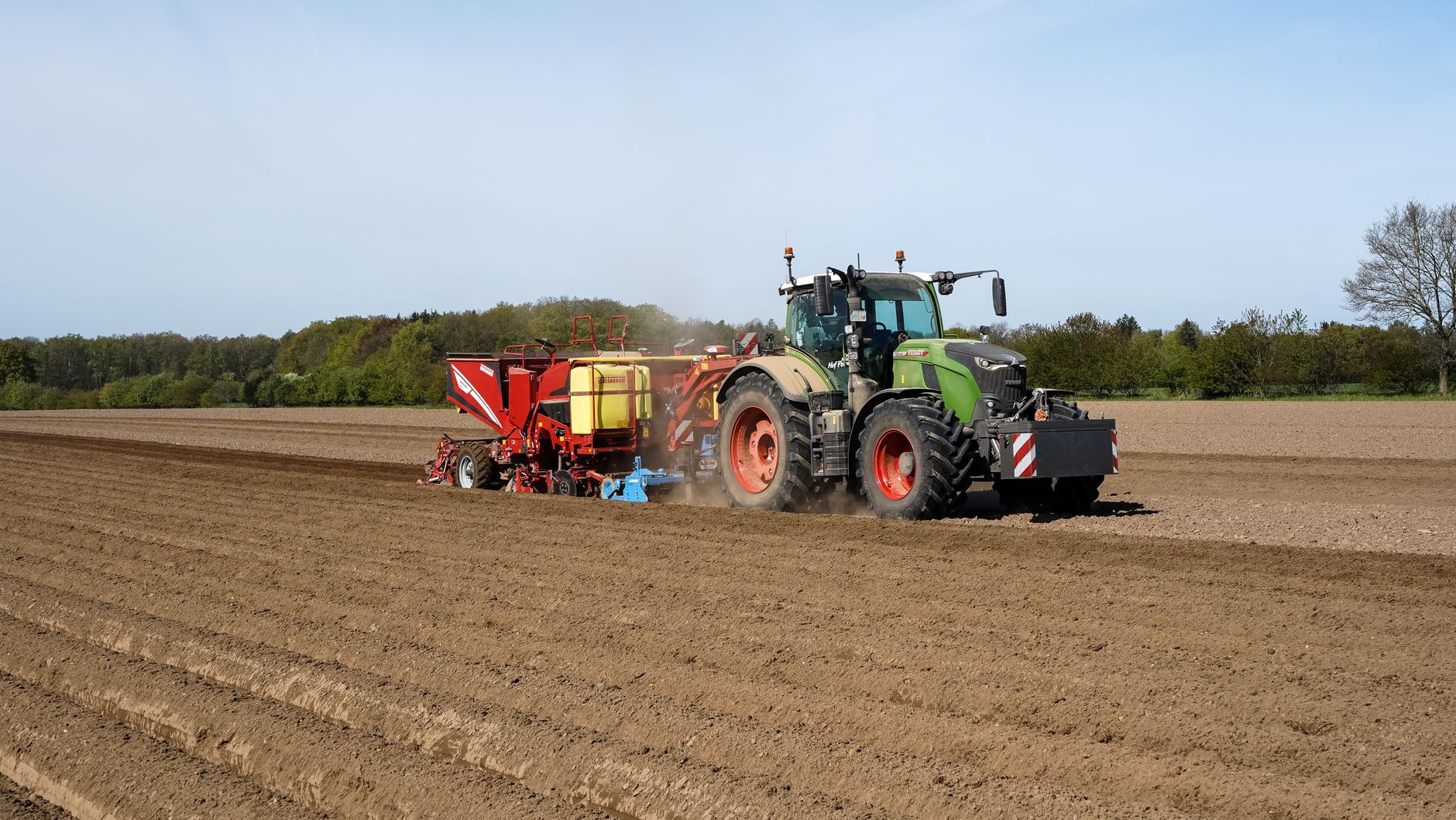 Tractor planting potatoes in Lütau, Germany during spring farming season.