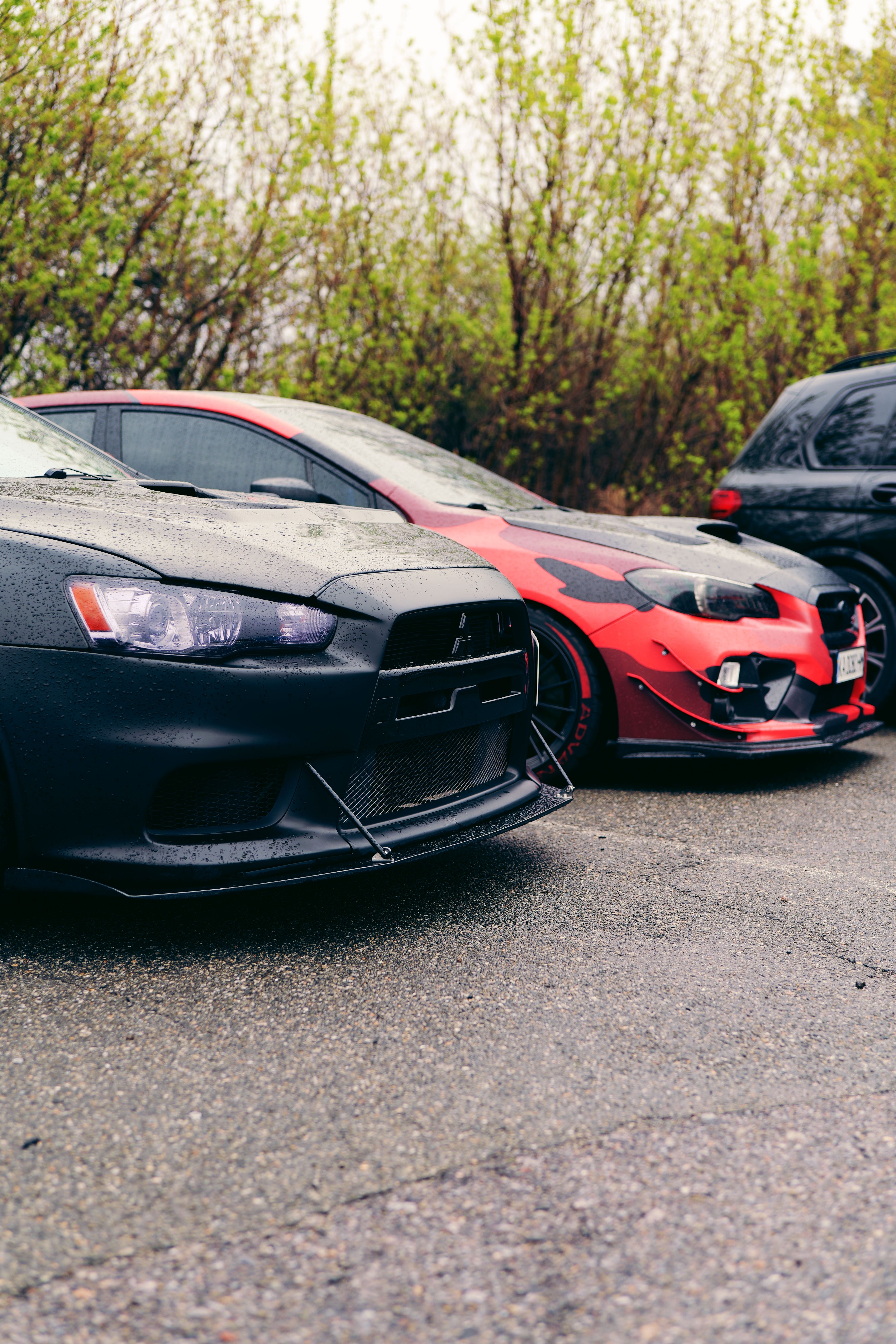 Sleek modified sports cars parked outdoors in a rainy setting in Ukraine, showcasing custom designs.