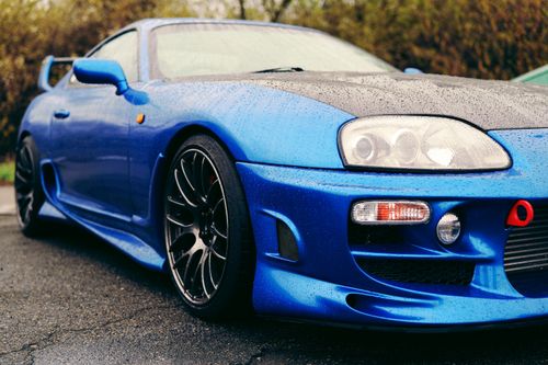 Free Dynamic low-angle shot of a blue sports car covered in raindrops, emphasizing its sleek design. Stock Photo