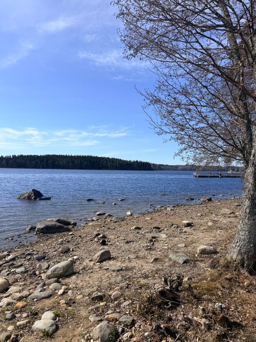 Free Tranquil lakeside view with rocky shore and clear skies in Savonlinna, Finland. Stock Photo