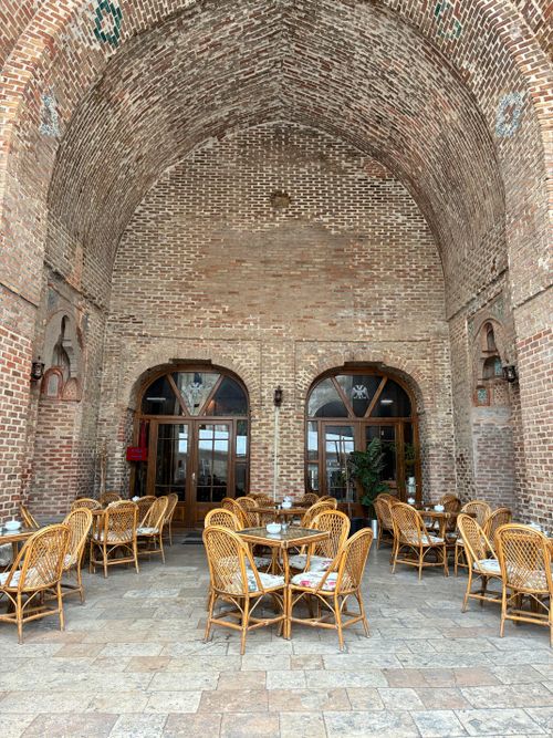 Free Rustic brick archway with charming outdoor café seating, natural tones. Stock Photo