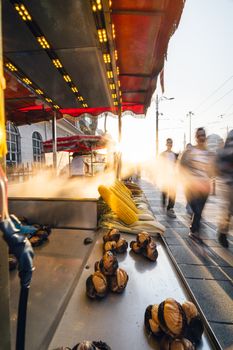 A bustling street food stand at sunset selling grilled corn and chestnuts, capturing a vibrant city life.