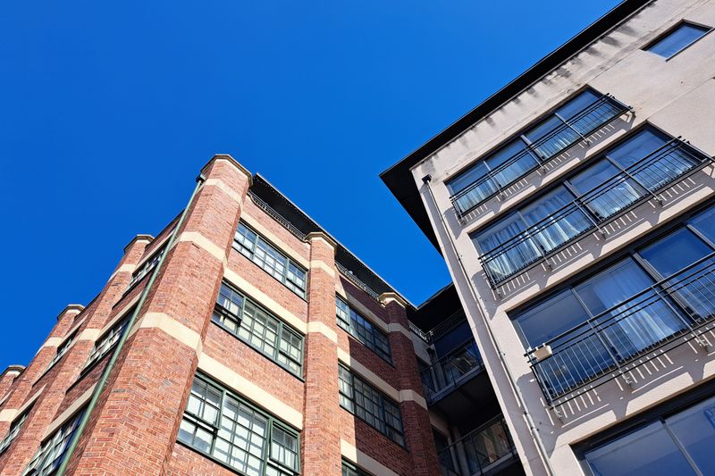 Stylish urban apartment buildings with balconies set against a clear blue sky, showcasing modern architecture.